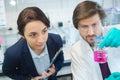 Scientists looking at pink liquid in glass flask