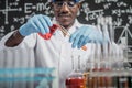 Scientists mix red and orange chemicals in a glass at the laboratory