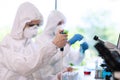 Scientists in protection suits and masks working in research lab using laboratory equipment: microscopes, test tubes. Royalty Free Stock Photo
