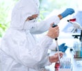 Scientists in protection suits and masks working in research lab using laboratory equipment: microscopes, test tubes.