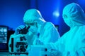 Scientists in protection suits and masks working in research lab using laboratory equipment: microscopes, test tubes Royalty Free Stock Photo