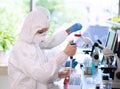 Scientists in protection suits and masks working in research lab using laboratory equipment: microscopes, test tubes. Royalty Free Stock Photo