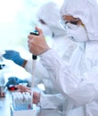Scientists in protection suits and masks working in research lab using laboratory equipment: microscopes, test tubes. Royalty Free Stock Photo