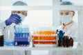 scientists in protective masks standing in front of a rack of test tubes . Royalty Free Stock Photo