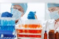 Scientists in protective masks standing in front of a rack of test tubes . Royalty Free Stock Photo