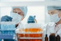 scientists in protective masks standing in front of a rack of test tubes . Royalty Free Stock Photo