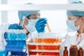 scientists in protective masks standing in front of a rack of test tubes . Royalty Free Stock Photo