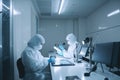 scientists in protective suits working with microscopes in modern laboratory. Biologists are working in a professional IVF