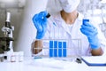 Scientists researching in laboratory in white lab coat, gloves analysing, looking at test tubes sample, biotechnology concept