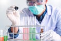 Scientists researching in laboratory in white lab coat, gloves analysing, looking at test tubes sample, biotechnology concept