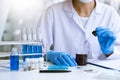 Scientists researching in laboratory in white lab coat, gloves analysing, looking at test tubes sample, biotechnology concept