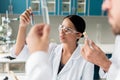 Scientists in white coats examining test tubes with reagents in chemical lab