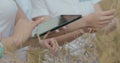 Scientists working in field with agriculture technology. Close up of woman hand touching tablet pc in wheat stalks