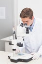 Scientist operating binocular microscope on laboratory bench with petri dish, probe and keyboard Royalty Free Stock Photo