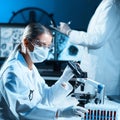 Scientists working in modern lab. Doctor making microbiology research. Laboratory tools: microscope, test tubes