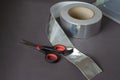 Scissors, aluminum tape, and a clear plastic container on a gray background