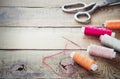 Scissors, bobbins with thread and needles. Old sewing tools on the old wooden background. Vintage Background