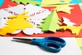 Scissors and Christmas paper figures made by children, on red paper sheet