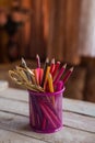 Scissors and colorful pencils of violet yellow pink red and orange in stationary cup on wooden table and background Royalty Free Stock Photo