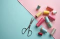 Scissors and colorful thread spools scattered on a pastel background. Crafting supplies for sewing and needlework. Top view flat Royalty Free Stock Photo