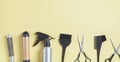 Scissors, comb and other hair styling tools on yellow background