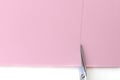 Scissors cut a sheet of pink paper in a line. Making a postcard in an envelope for Valentine`s Day. Do it yourself. Photo from th