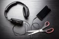 Scissors cut the wire from the headphones, leading to the phone, and thus stop the very loud illegal pirated music Royalty Free Stock Photo