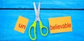 Scissors cut the word unbelievable. concept believable. cuts the word Royalty Free Stock Photo