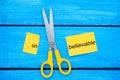 Scissors cut the word unbelievable. concept believable. cuts the word Royalty Free Stock Photo