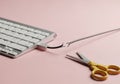 Scissors cutting keyboard cable on pink. Royalty Free Stock Photo