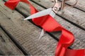 Scissors cutting red ribbon, close-up view on blue Royalty Free Stock Photo