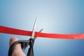 Scissors are cutting red ribbon. Opening ceremony concept. Isolated on blue background Royalty Free Stock Photo