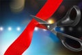 Scissors cutting red ribbon on bokeh background