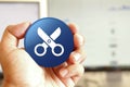 Scissors icon blue round button holding by hand infront of workspace background
