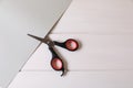 Scissors and paper on white wooden background, top view. Space for text Royalty Free Stock Photo