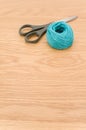 Decorative rustic cyan yarn ball and scissors on a wooden tabletop with copy space