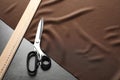 Scissors, ruler and fabric on grey table. Tailoring equipment