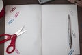 Scissors and stationary with checkered math book above textured backdrop. Writing equipment on an unplain floor