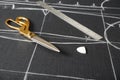 Scissors, tailor`s chalk and ruler on grey fabric with sewing patterns