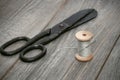 Scissors and a wooden spool of thread and needle. Old sewing tools on a wooden background. vintage background Royalty Free Stock Photo