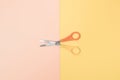 Scissors with yellow and orange handle on pastel pink and yellow background. Minimal design Royalty Free Stock Photo