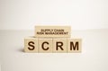 SCM abbreviation. Wooden cubes with letters, on a table with a magnifying glass. Green background. Business concept image