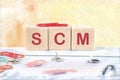 SCM short for Supply Chain Management. SCM assembled from cubes on a yellow background Royalty Free Stock Photo