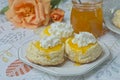 Scones with apricot jam and whipped cream on a table with jar of jam