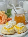 Scones with apricot jam and whipped cream on a table with jar of jam