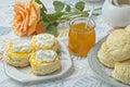 Scones with apricot jam and whipped cream on a table with jar of jam