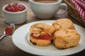 Scones with cream and jam on plate and coffee cup