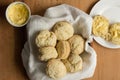 Scones in a dish towel with sliced scones, buttered in a plate on wooden table