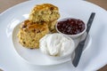 Scones with jam and cream on white plate
