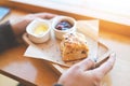 Scones and jam on wooden plate, woman served scones and cream for dessert and tea - fresh homemade butter scones Royalty Free Stock Photo